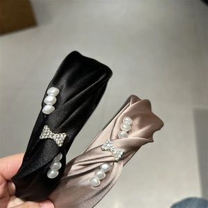 Close-up of silk knot headbands in black and champagne with pearls and rhinestone bows