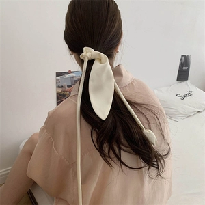 Elegante scrunchie in seta color crema con lunghi nastri mostrato su capelli da dietro