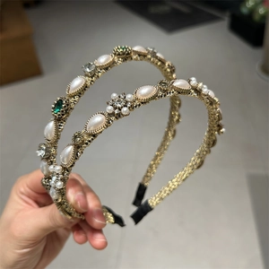 Baroque style gold headband with white pearls and emerald gemstones in a vintage design
