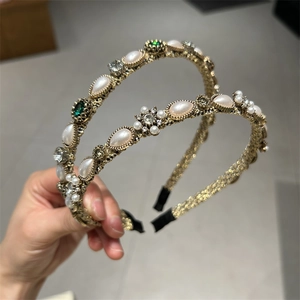 Detail view of gold headband set with emerald crystals and imitation teardrop pearls