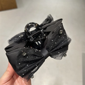 Detail der schwarzen Organza-Schleife mit glitzernden Strasssteinen und stabiler Haarklammer