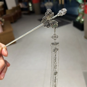 Dettaglio del fermaglio a farfalla con lunghe nappe argentate e design in stile vintage