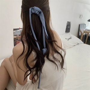 Dettaglio dell'elegante elastico in seta blu con nastri lunghi sui capelli mossi