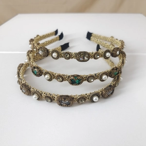 Close-up of three vintage gold braided headbands with pearls and emerald green gemstones