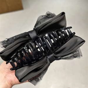 Detailansicht der schwarzen Haarklammer mit Satinschleife und Pailletten-Organza