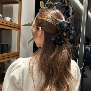 Detail einer eleganten schwarzen Organza-Schleifen-Haarklammer mit Strass auf dem Modell