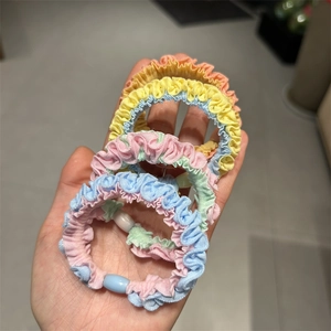Detail view of four macaron colored elastic scrunchies with pleated fabric texture