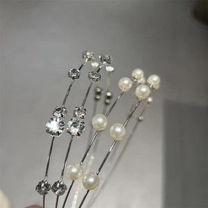 Close-up of slim silver metal headbands featuring white pearls and sparkling rhinestones