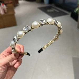 Detail view of woven gold headband featuring white pearls and square clear rhinestones