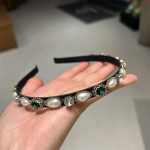 Detailed macro view of retro baroque headband with green gemstones and white pearls