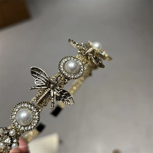Macro shot of vintage gold bee headband with inlaid pearls and sparkling rhinestones