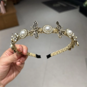 Detailed macro view of vintage gold bee headband with pearls and sparkling crystals