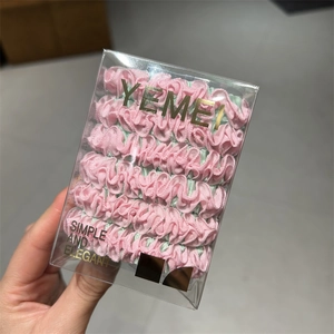 Detail of pink and green pleated hair scrunchies set in a transparent gift box