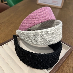 Detailed texture of pink, beige and black tweed headbands on a wooden jewelry tray