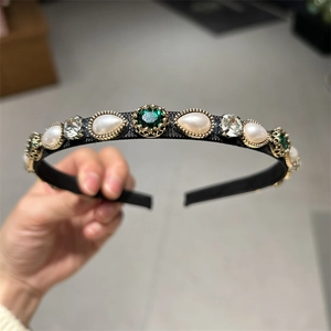 Detail of vintage velvet headband featuring pearls and emerald green crystals in gold settings