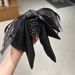 Detail von mehrlagiger schwarzer Haarklammer mit Schleife und glitzernden Bändern