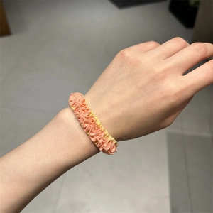 Pink and yellow ruffled scrunchie hair tie worn on wrist showing elastic pleated texture