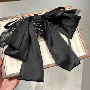 Detail einer luxuriösen schwarzen Schleifen-Haarklammer mit eleganten Organza-Streamern