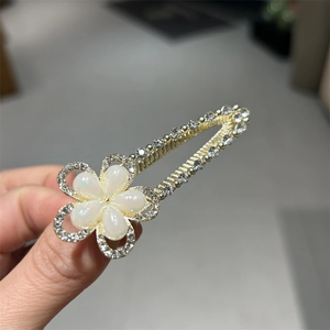 Barrette dorée en goutte d'eau avec fleur en résine blanche et strass brillants