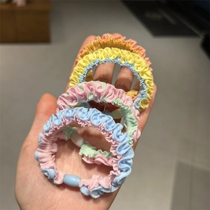 Close-up of four macaron-colored elastic hair ties with pleated fabric texture set