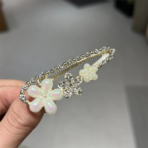 Gros plan détaillé d'une pince à cheveux dorée ornée de strass et de fleurs en émail