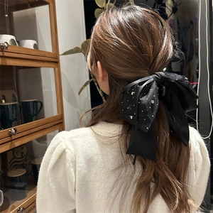 Detailaufnahme der schwarzen Satin-Schleife Haarklammer mit Strasssteinen auf langem Haar