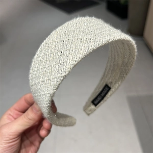 Detail view of thickened cream woven headband with HAND MADE label on textured fabric