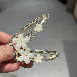 Détail de barrettes à fleurs dorées élégantes avec pétales nacrés et cristaux brillants