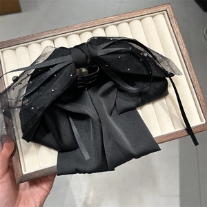 Detail einer luxuriösen schwarzen Organza-Schleife-Haarklammer mit glänzenden Strasssteinen