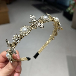 Close-up of golden pearl headband with detailed metal bee accents and elegant vintage finish