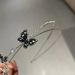 Close-up of a silver headband featuring black glitter butterfly and sparkling rhinestones