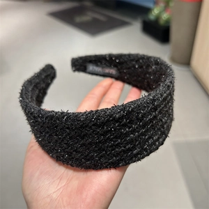 Close-up of black tweed headband with silver sequins and Hand Made woven label