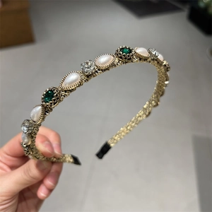 Detail of vintage gold headband with pearls, green gemstones, and sparkling zircons