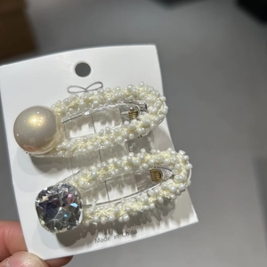 Dettaglio di due fermagli per capelli con perle sintetiche e strass scintillanti