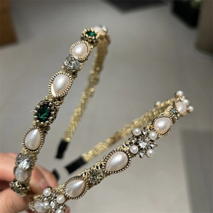Detailed macro view of vintage gold headband with emerald crystals and white pearls