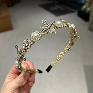 Detail of vintage gold headband featuring small bee charms, pearls, and rhinestones