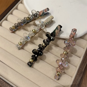 Detail of crystal beaded hair clips with fabric-wrapped bases in a jewelry box
