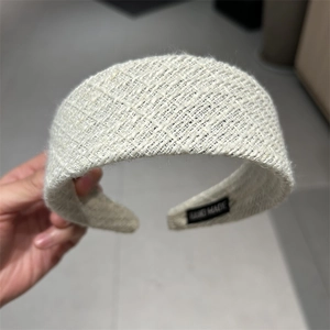 Close-up of cream woven tweed headband with hand made tag and textured fabric detail