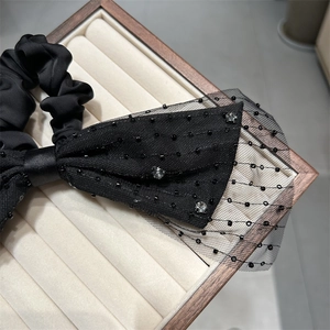 Detail einer eleganten schwarzen Haarklammer mit Polka-Dot-Netz und funkelnden Strass