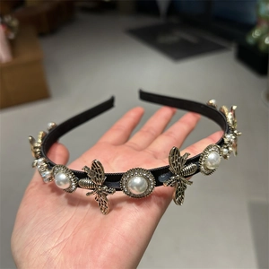 Close-up of vintage thin headband featuring gold bee charms and pearls with crystal accents