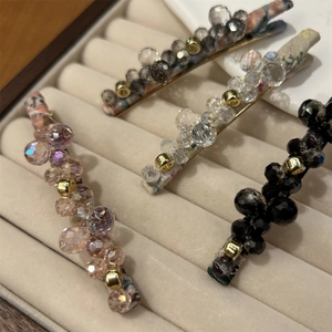 Detail view of handmade crystal bead hair clips in four elegant colors on beige velvet