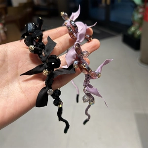 Detail of handmade headbands with crystal beads and elegant fabric bows in purple and black