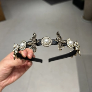 Detail of a thin black headband with white pearls, rhinestones, and vintage gold bees