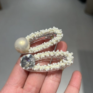 Dettaglio di fermagli per capelli fatti a mano con perle e strass su base chiara