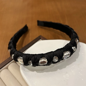 Close-up of elegant black silk headband with sparkling crystals on a ceramic tray