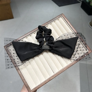 Detail eines handgefertigten schwarzen Satin-Haarclips mit Mesh-Schleife und Etikett
