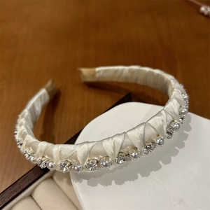 Close-up of handmade cream fabric headband with shimmering pearls and crystal rhinestones
