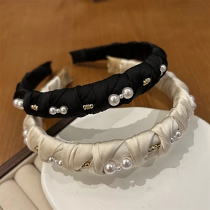 Elegant black and beige satin headband with pearls and gold beads on a white display
