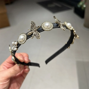 Detailed close-up of retro golden bee ornaments and white pearls on a black headband