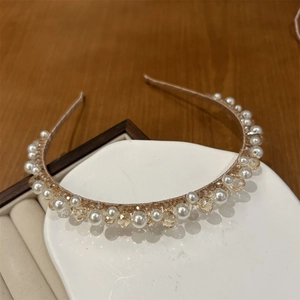 Detail of hand-wrapped champagne crystal and pearl headband on white display tray